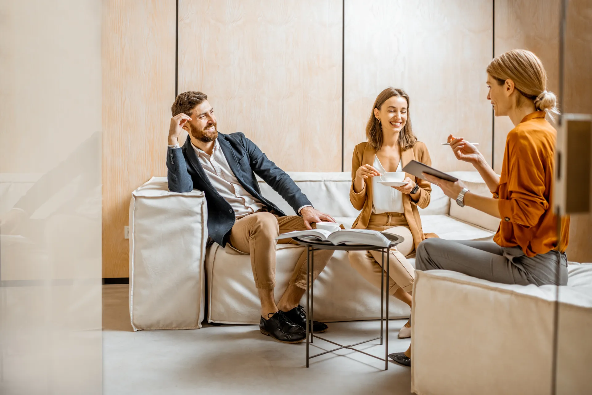 Three colleagues reviewing a listing flyer together on a tablet in a warm, wood-paneled office.